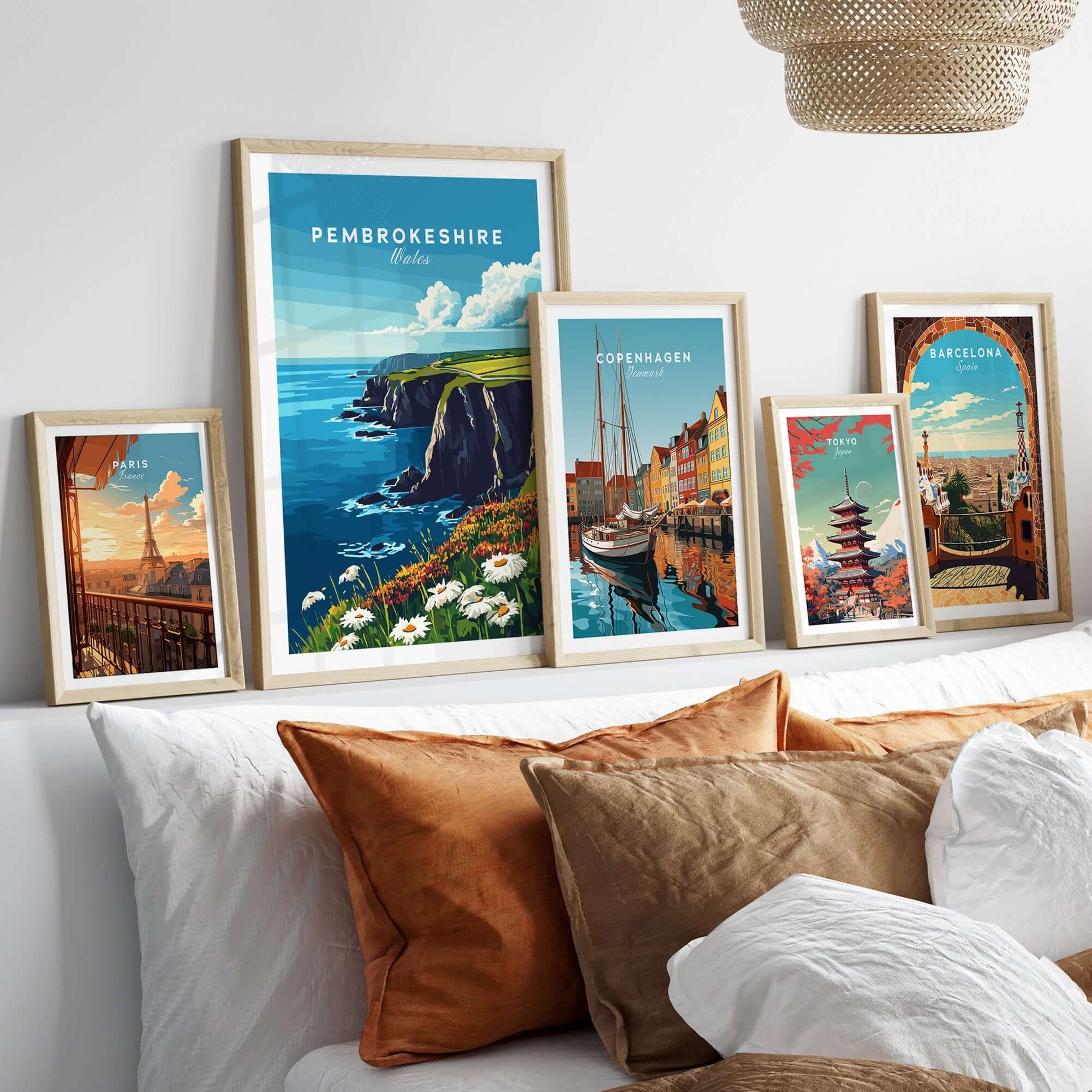 Pembrokeshire Wall Art showcasing coastal views and framed prints of various cities on a bed with decorative pillows.