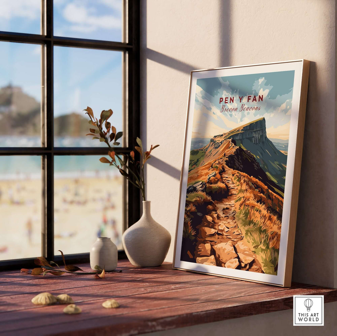 Pen Y Fan travel print showcased in a sunlit room with plants and a beach view outside the window.