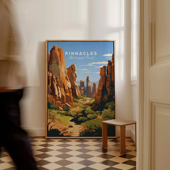 Framed Pinnacles National Park travel poster on floor, man walking past in bright hallway