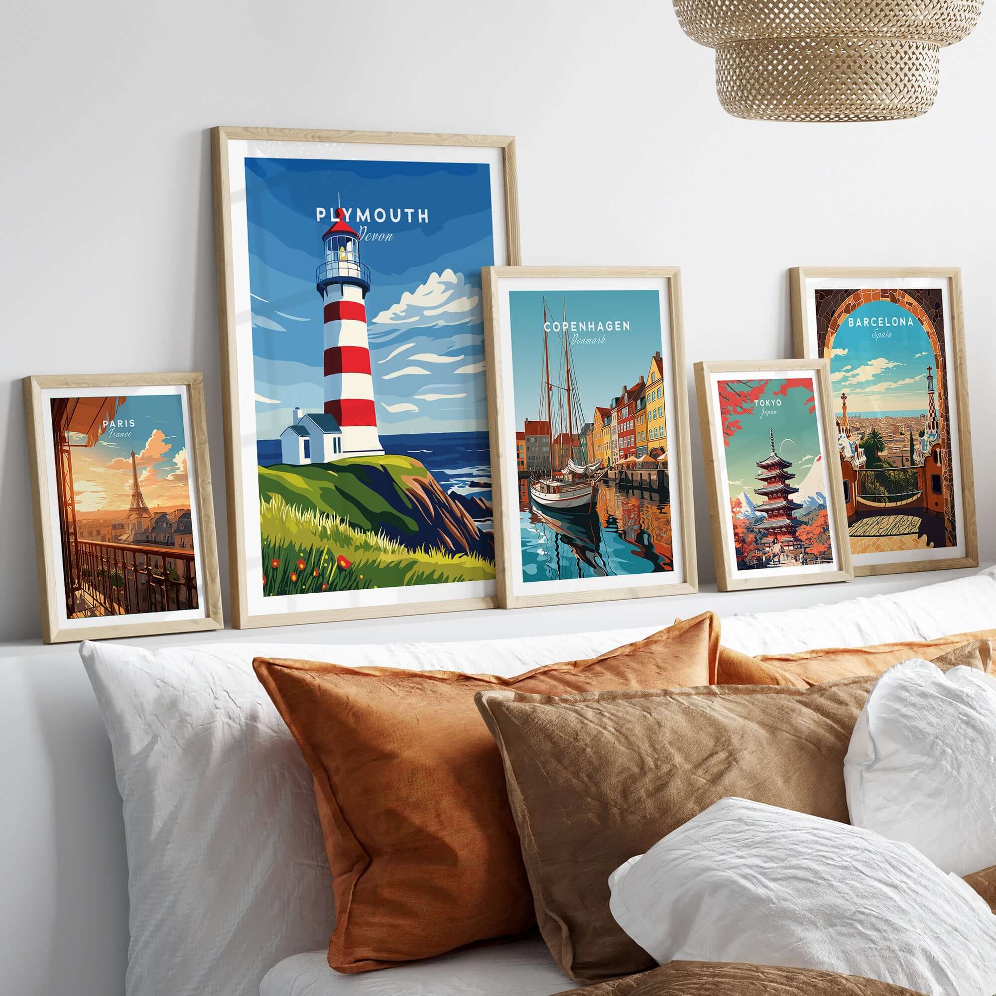 Plymouth Lighthouse Art - Seaside View Travel Poster displayed among other framed travel posters on a decorative bed.