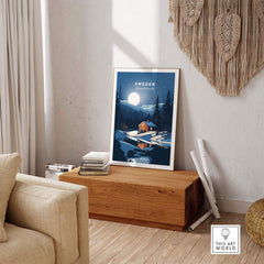 Sweden art print displayed in a cozy living room, featuring a serene winter landscape with a cabin and moonlight.