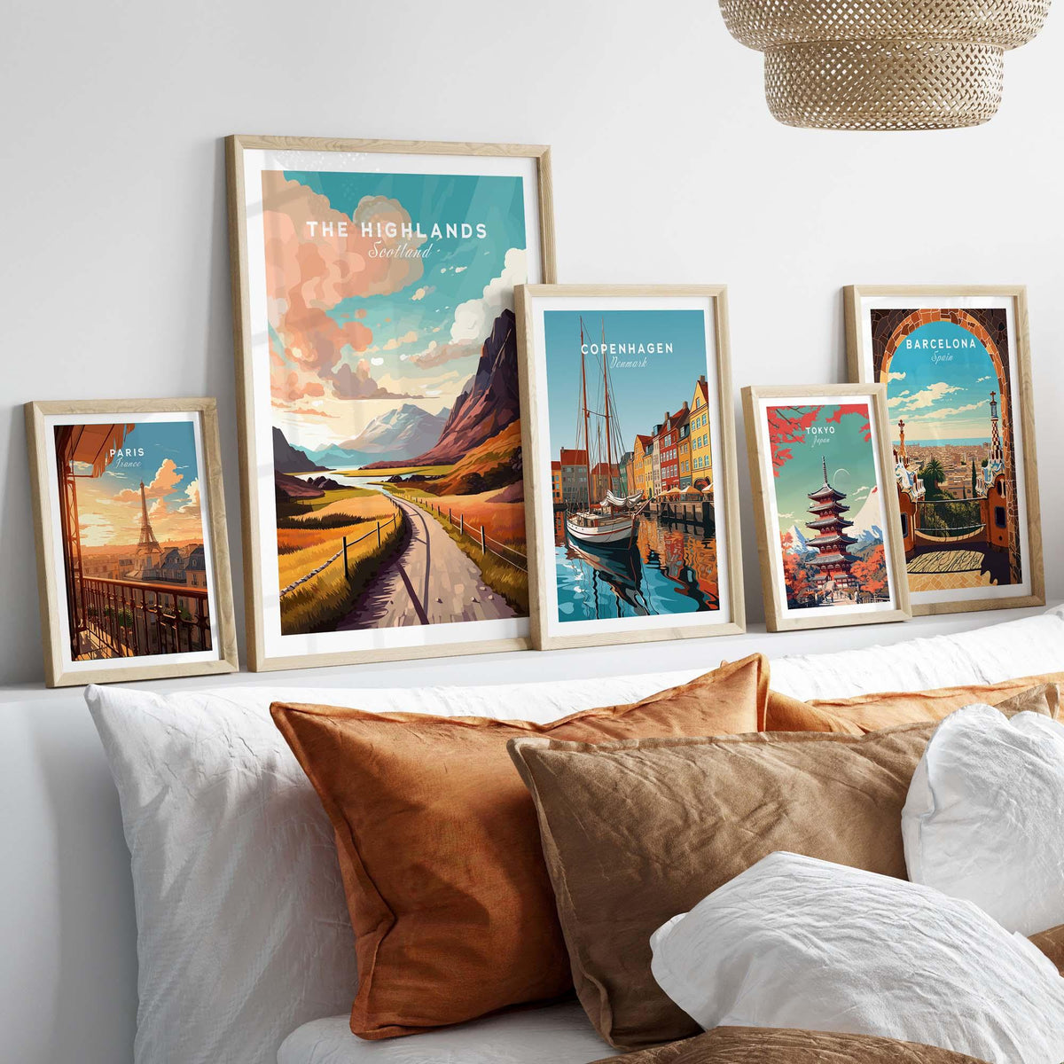 Framed posters of city skylines on a wall above a cozy bed with decorative pillows.