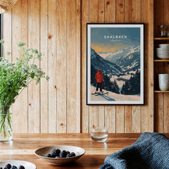 Saalbach Travel Poster - Austria displayed on a wooden wall, showcasing scenic mountain views and a skier in red.
