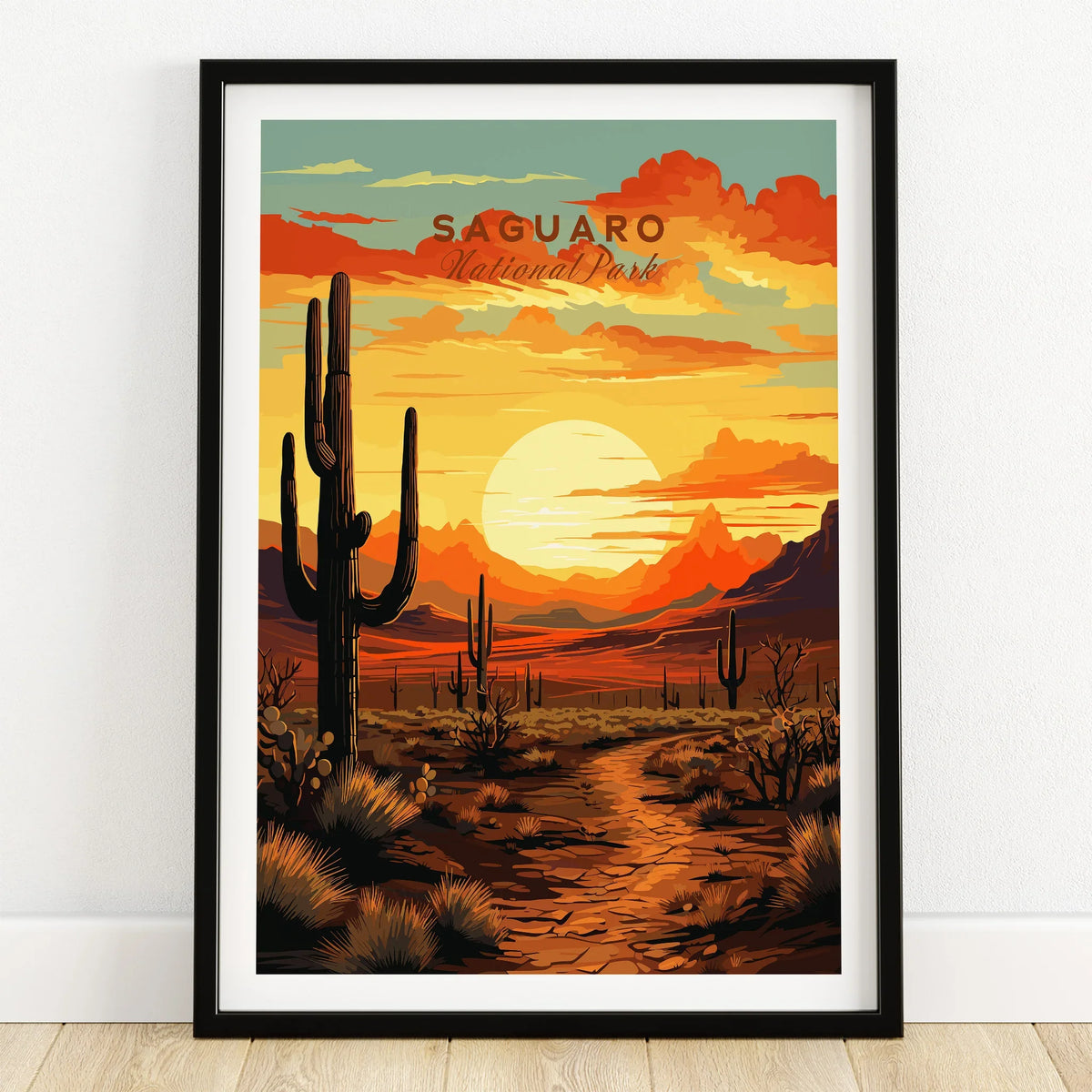 Saguaro National Park art print in black frame on wooden floor, sunset desert landscape.