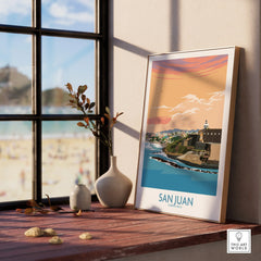 San Juan Puerto Rico travel poster with coastal cityscape, sunset sky, and lighthouse, displayed on windowsill.