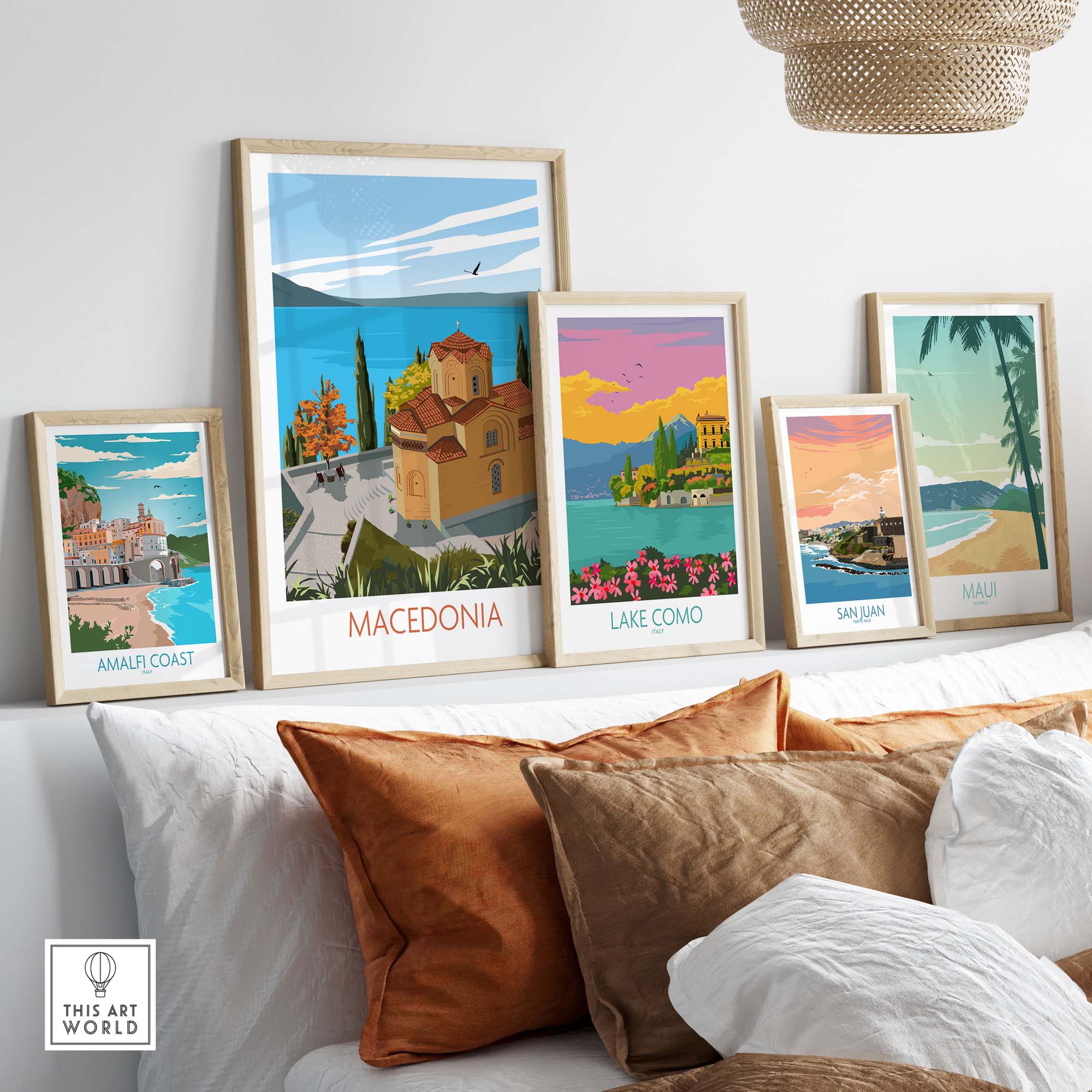 Collection of framed art prints featuring Macedonia, Lake Como, Amalfi Coast, San Juan, and Maui on a stylish couch.