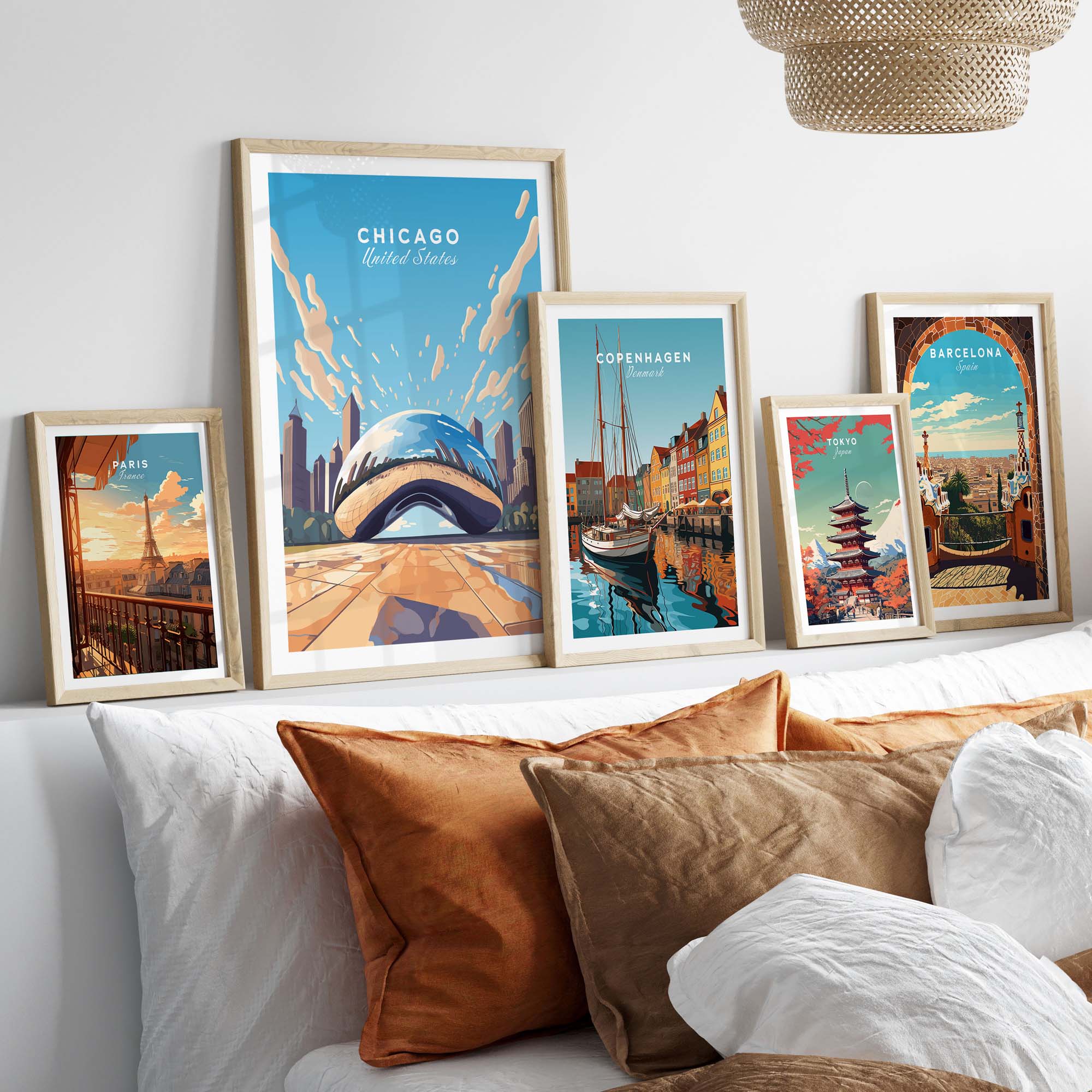 Collection of vibrant city posters in frames, featuring Chicago, Copenhagen, and Barcelona decor on a cozy bed.