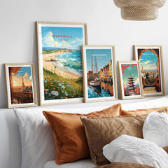 Cornwall art print displayed with other city prints on a wall above a cozy sofa, showcasing beach and travel themes.