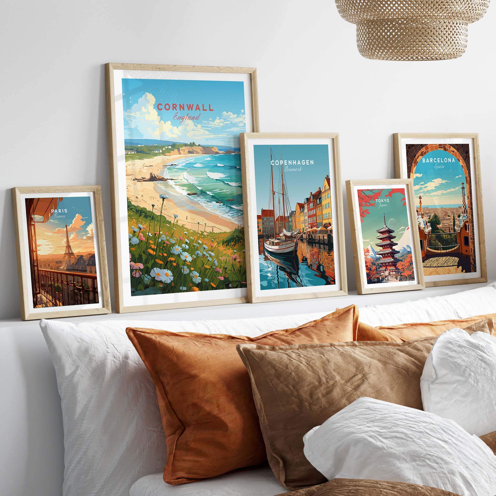 Cornwall art print displayed with other city prints on a wall above a cozy sofa, showcasing beach and travel themes.