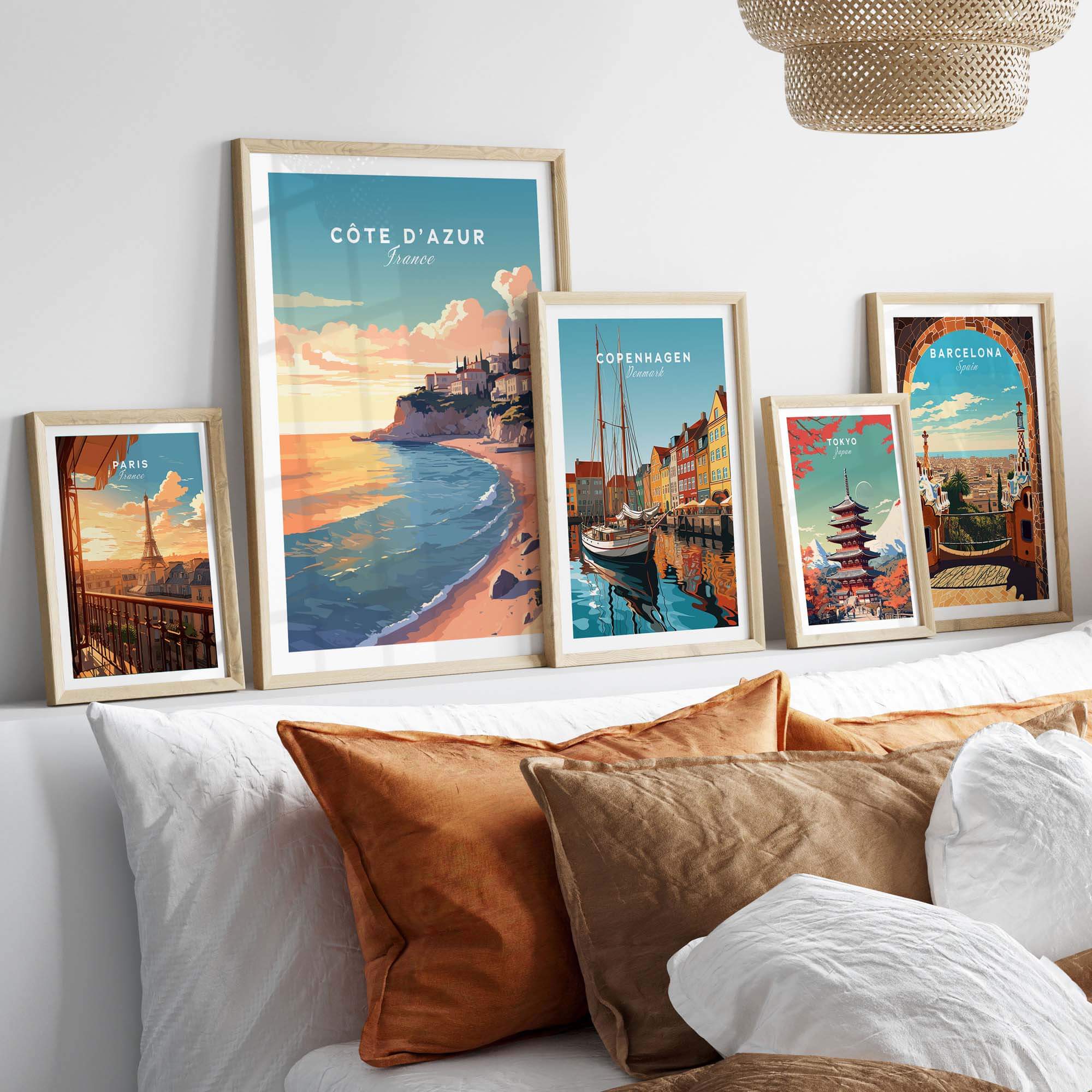 Colorful Côte d'Azur travel poster prints displayed on a cozy bed, enhancing wall art aesthetics.