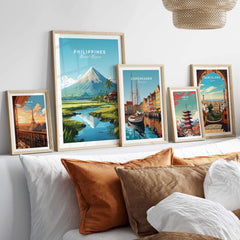 Philippines travel poster featuring Mount Mayon, displayed among various international art prints on a cozy sofa.