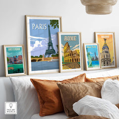 Framed travel poster prints of Paris, Rome, Madrid, Amsterdam, and New York displayed in a stylish living room setting.
