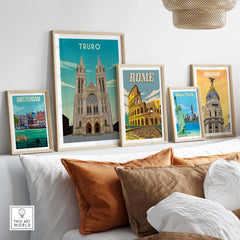 Framed travel poster prints featuring Truro, Rome, Amsterdam, New York, and Madrid on a stylish sofa.
