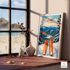 Ski poster of Stowe Vermont framed on a windowsill with scenic mountain view and skis, perfect for skiing enthusiasts.