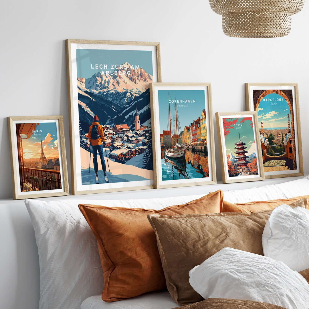 Ski prints of Lech Zürs am Arlberg and other cities displayed in stylish frames on a cozy bed with decorative pillows.