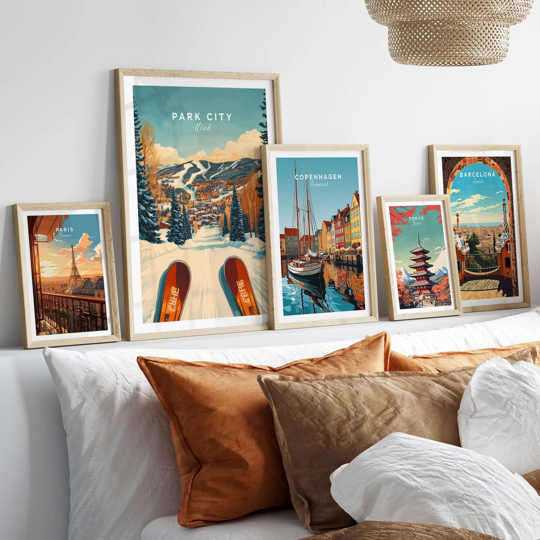 Collection of framed travel posters including Park City, Utah, showcasing winter sports and vibrant cityscapes on a cozy sofa.