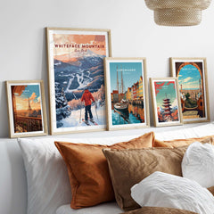 Collection of ski and travel prints including Whiteface Mountain New York, displayed on a modern wall above a cozy couch.