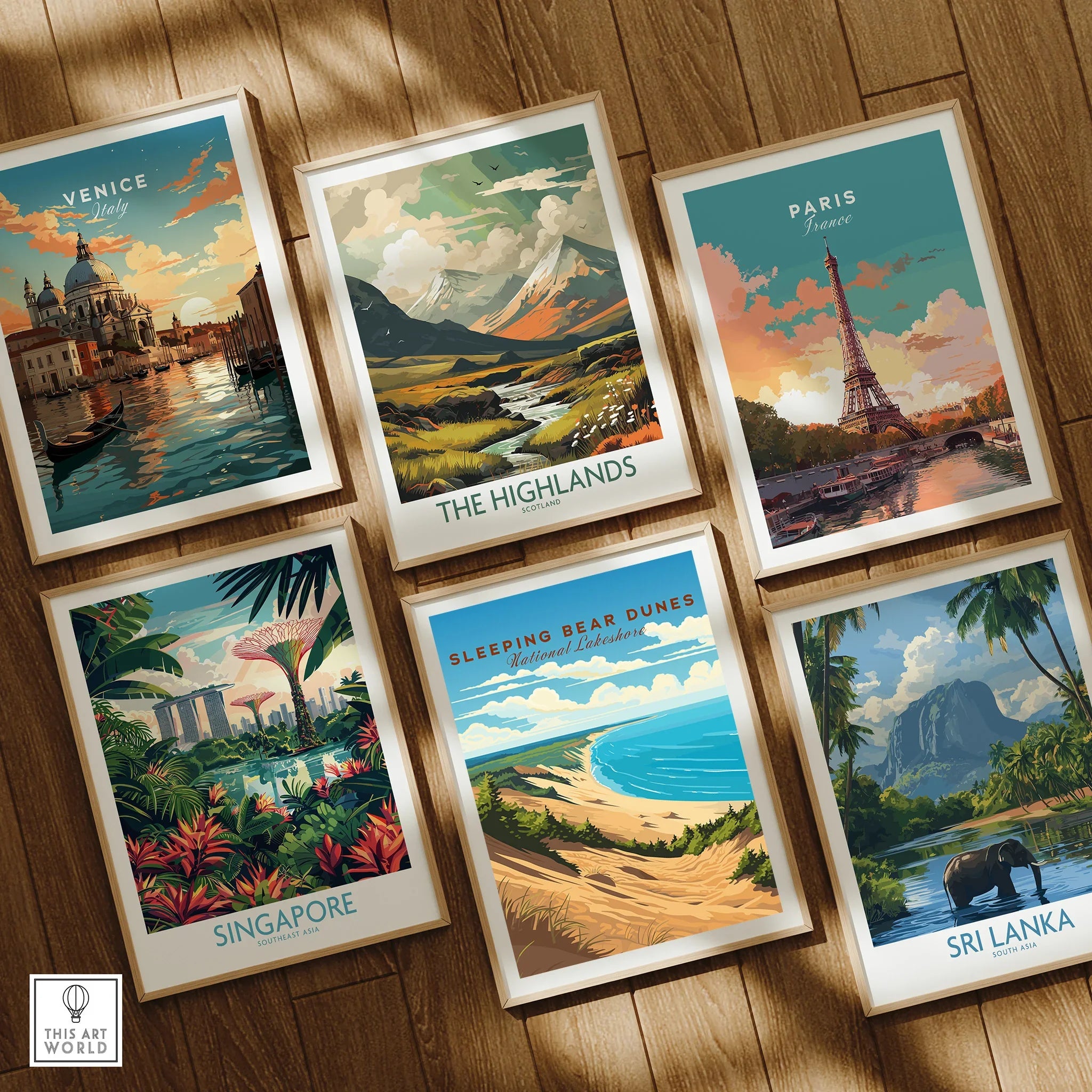 Set of six framed travel and national park art prints on wooden floor, featuring Venice, Paris, The Highlands, Singapore, Sleeping Bear Dunes, and Sri Lanka.