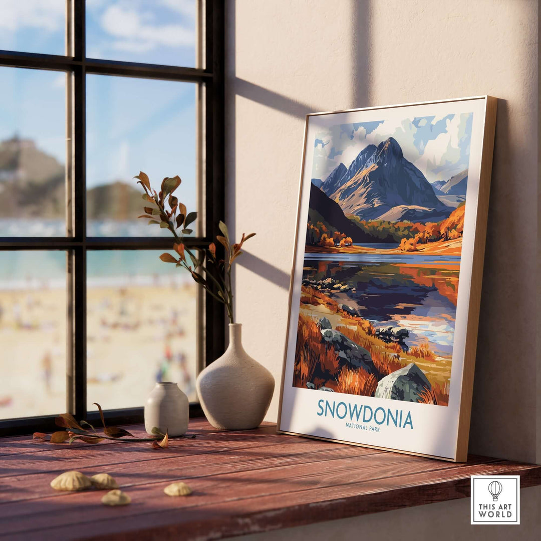 Snowdonia National Park poster showcasing autumn colors and mountains, displayed by a window in a cozy interior setting.