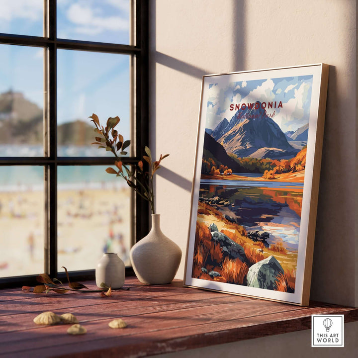 Snowdonia National Park print featuring vibrant autumn colors displayed on a wooden table by a window.