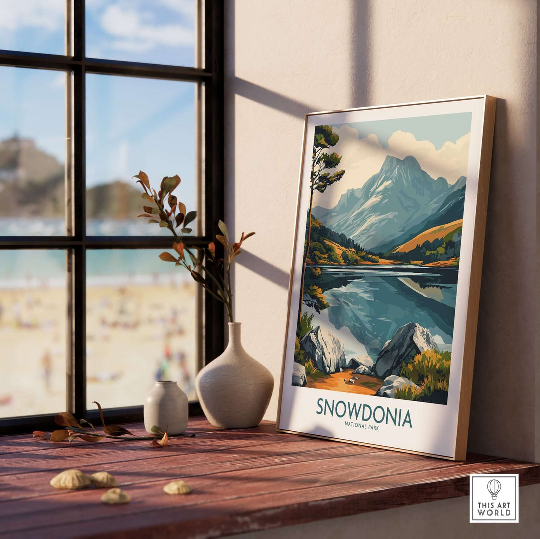 Snowdonia National Park travel poster showcasing mountains, lakes, and vibrant landscapes, displayed by a window.