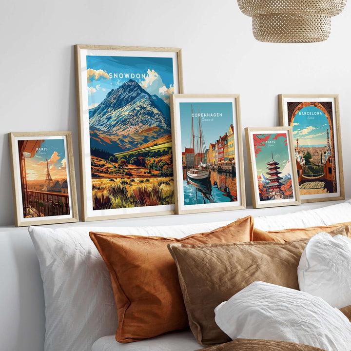 Collection of travel posters featuring Snowdonia, Copenhagen, and Barcelona displayed on a cozy sofa backdrop.