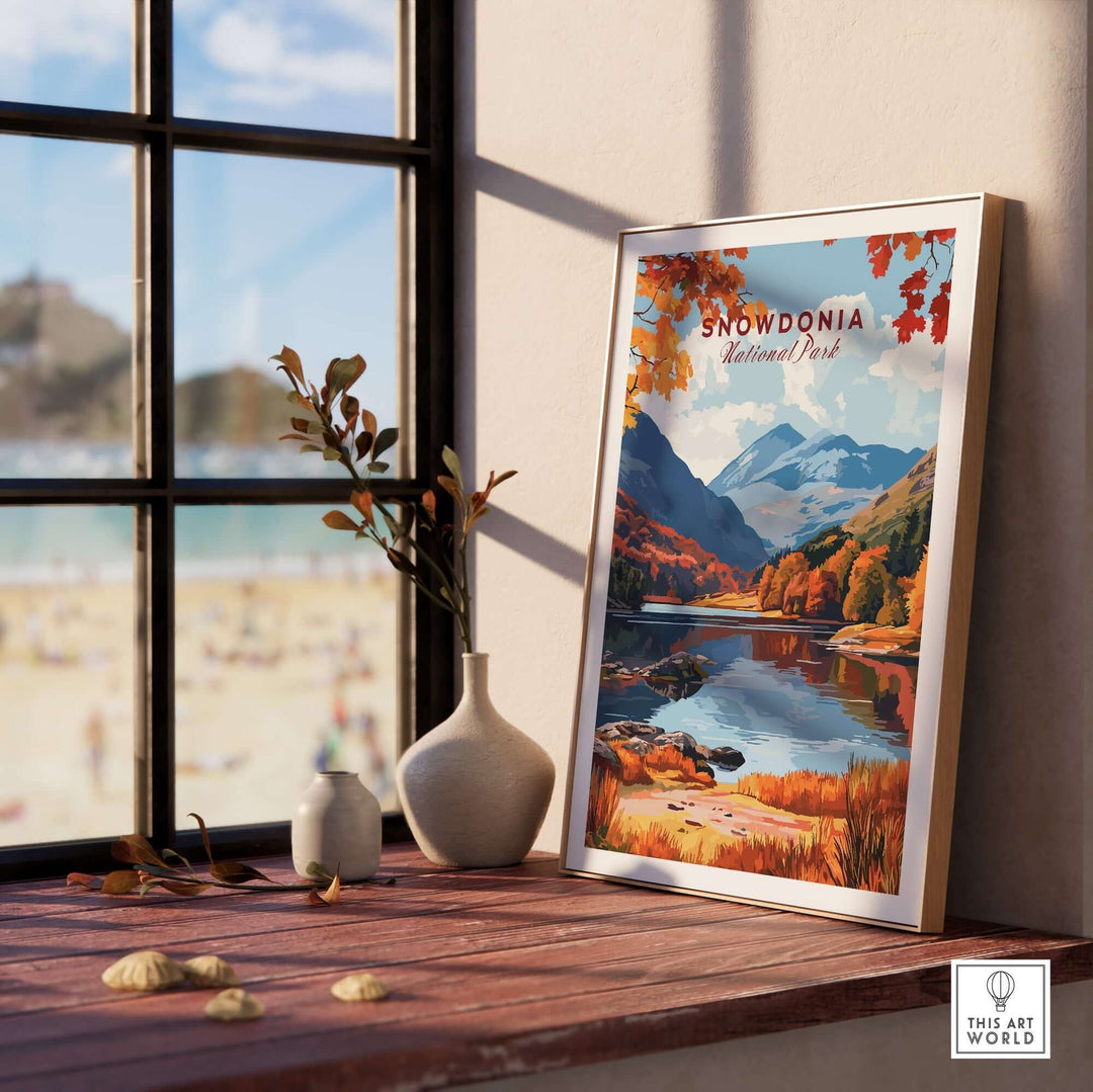 Snowdonia National Park wall art framed on a wooden table near a window, showcasing autumn landscapes and serene reflections.