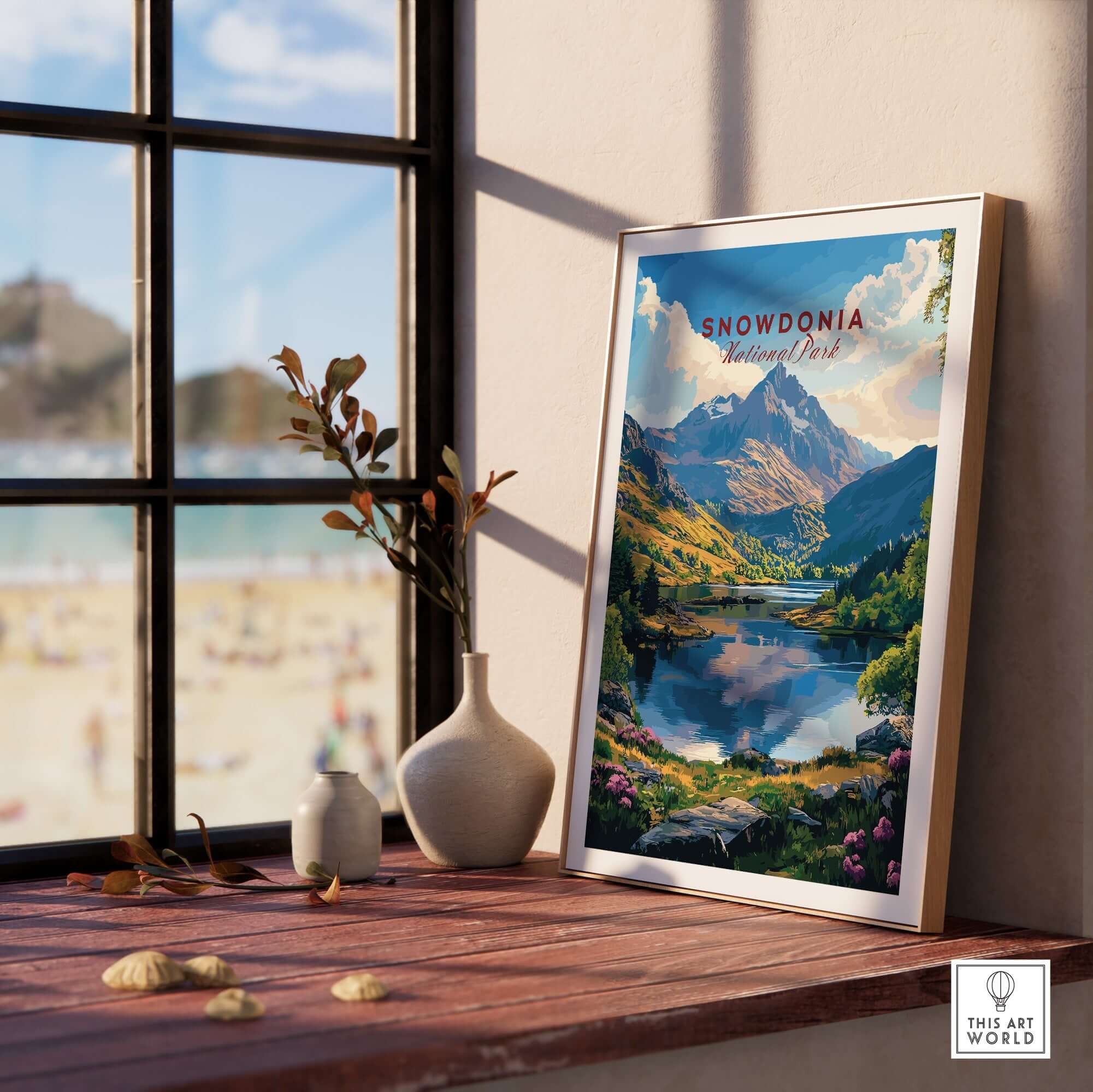 Snowdonia National Park Wall Art Poster displayed on a windowsill with mountains and lake backdrop.