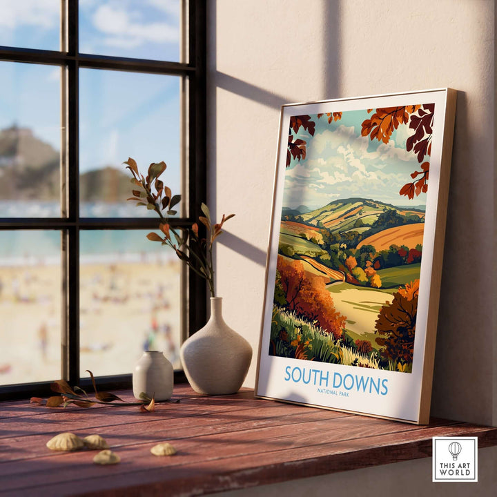 South Downs National Park art print displayed on a wooden table near a window, showcasing vibrant landscapes and autumn colors.