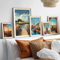 The Broads National Park Travel Print and other travel-themed art framed on a wall above cushions.