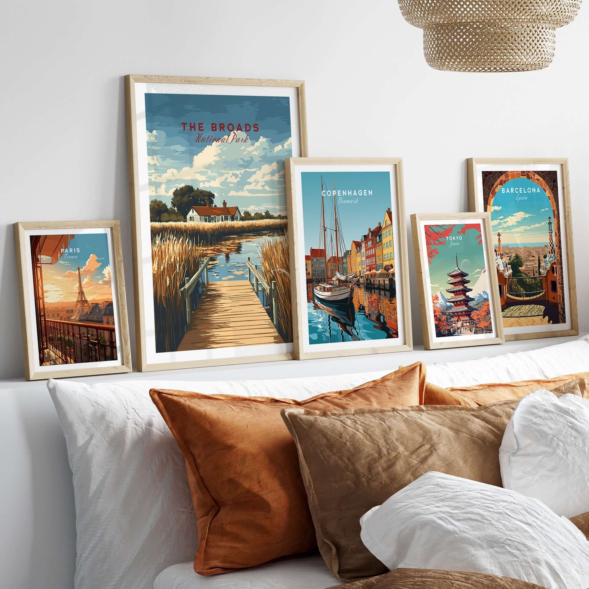 The Broads National Park Travel Print and other travel-themed art framed on a wall above cushions.