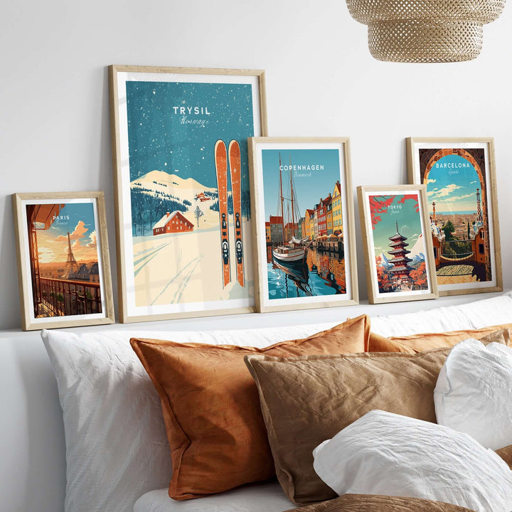 Five framed travel art prints including Trysil, Copenhagen, and Barcelona displayed on a stylish wall above cozy cushions.