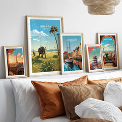 Framed Uganda travel poster print among other travel art prints on a cozy sofa.
