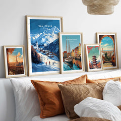 Framed Val Cenis ski print and cityscape prints on a wall above a cozy bed with decorative pillows.