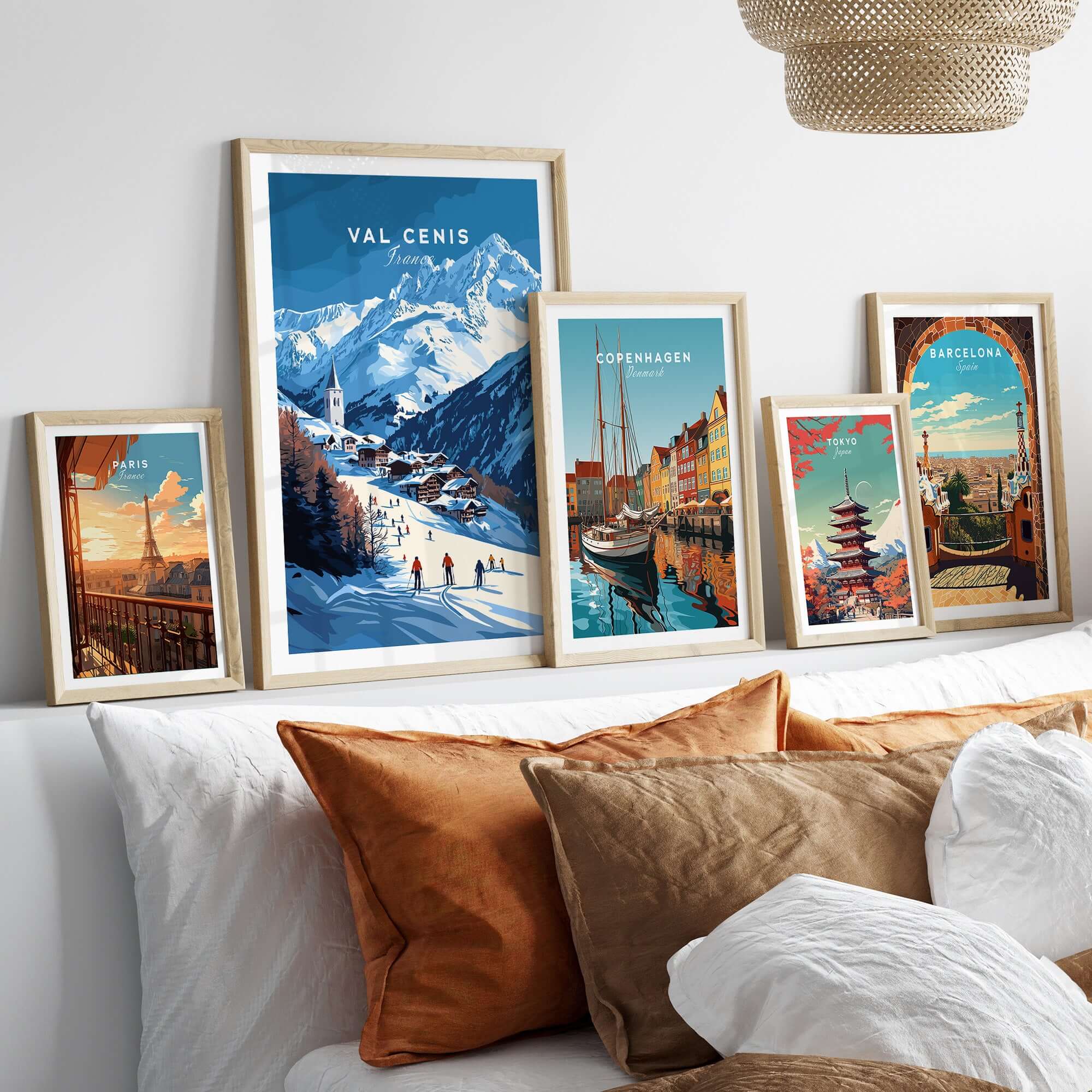 Framed Val Cenis ski print and cityscape prints on a wall above a cozy bed with decorative pillows.