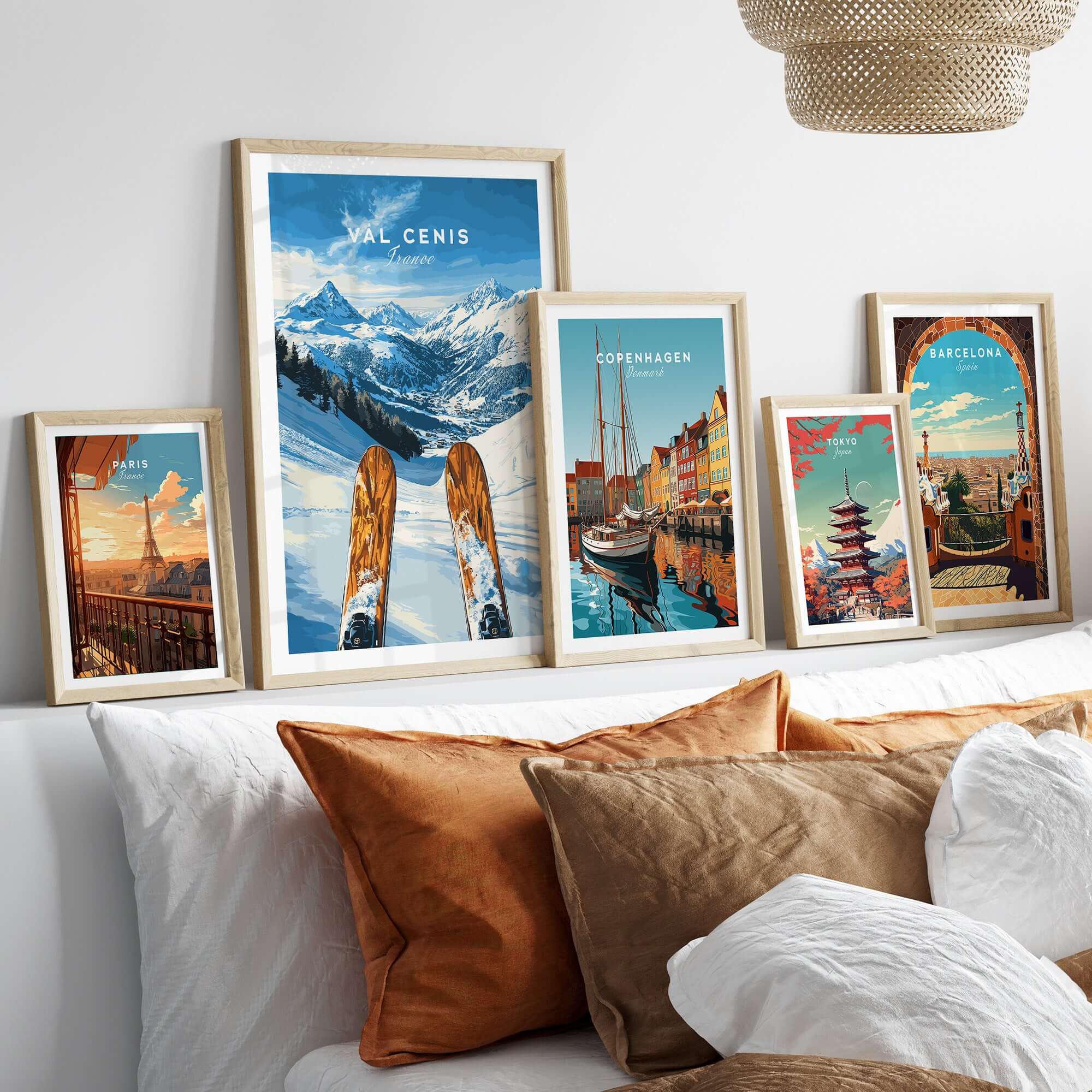 Collection of framed Val Cenis and travel posters displayed on a stylish bed with decorative pillows.