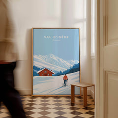 Val-d'Isère Poster France featuring a skier in front of a snowy landscape and a charming cabin.