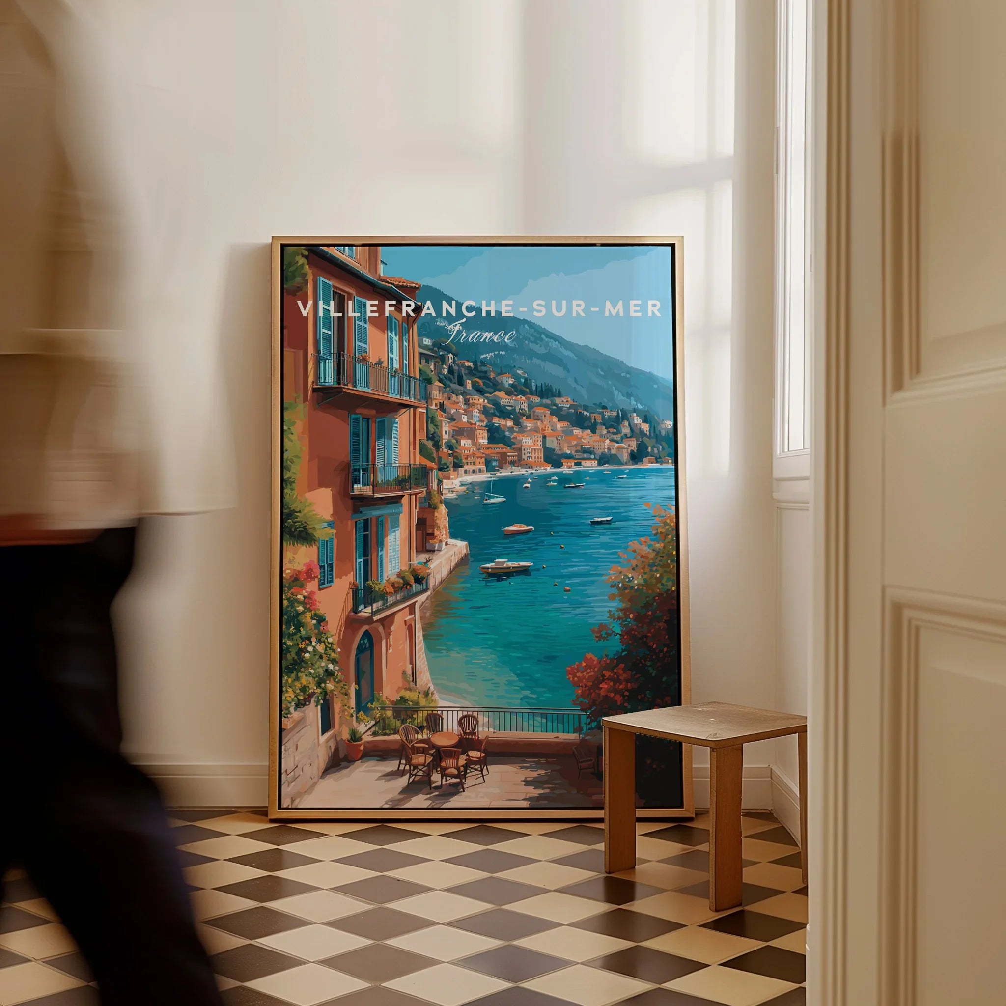 Framed Villefranche-sur-Mer travel poster with Mediterranean view leaning on floor in bright room