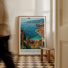 Framed Villefranche-sur-Mer travel poster with coastal art leaning on wall in a bright room