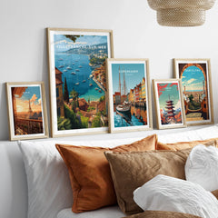 Set of five framed travel posters above bed, featuring Paris, Villefranche-sur-Mer, Copenhagen, Tokyo, and Barcelona.
