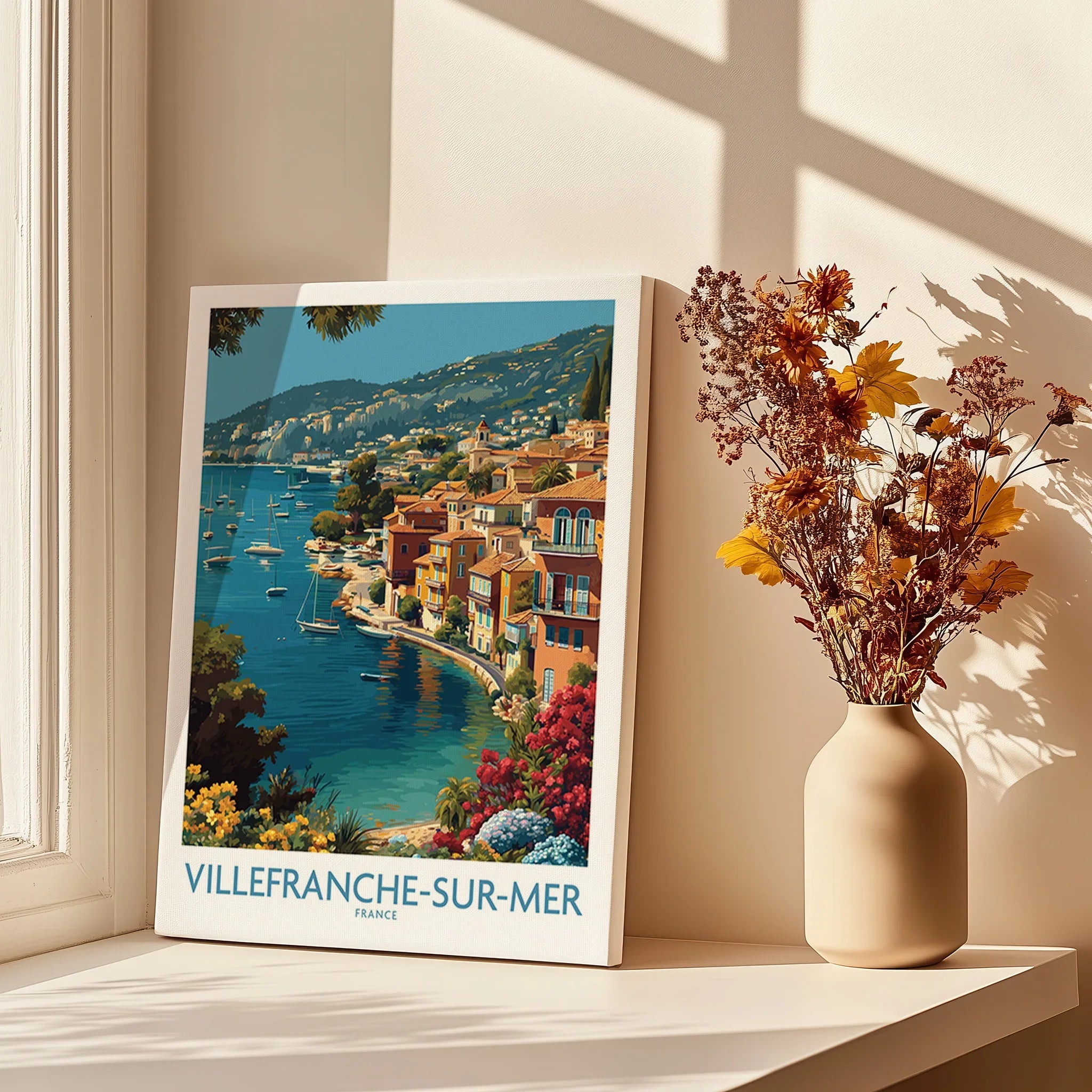 Villefranche-sur-Mer travel poster on canvas by a sunny window with a vase of dried flowers.