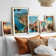 Set of five framed travel art prints above bed showcasing Paris, Villefranche-sur-Mer, Copenhagen, Tokyo, and Barcelona.