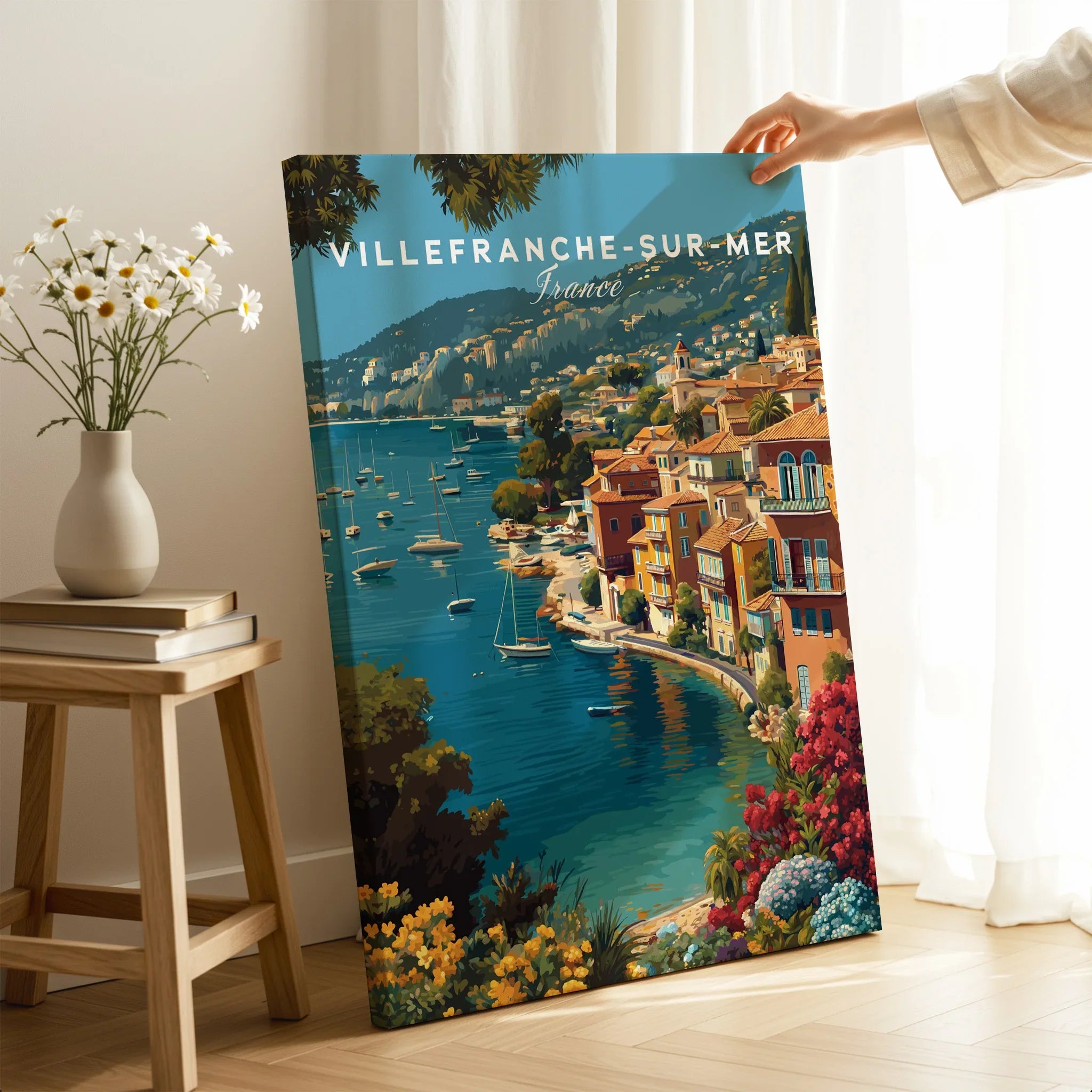 Villefranche-sur-Mer France travel poster canvas print with vibrant coastal art, hand holding edge in a bright room.