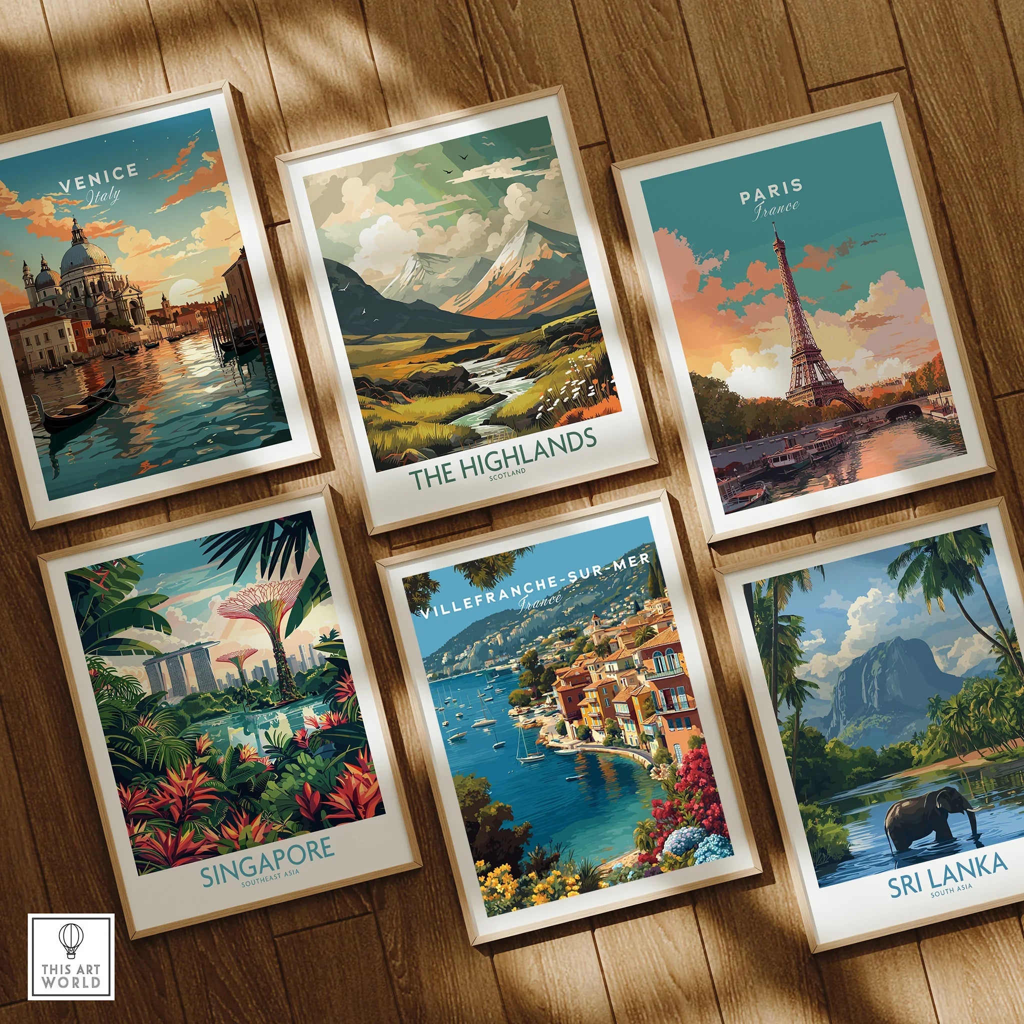Set of six framed travel art prints on wooden floor featuring Venice, Paris, Singapore, The Highlands, Villefranche-sur-Mer, and Sri Lanka.