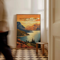Framed Waterton Lakes National Park travel poster on floor, man walking past in hallway.