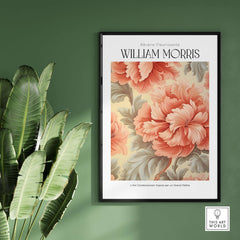 William Morris Prints - Pink Peony Pattern Art Print - Floral Botanical Poster on a green wall beside tropical leaves.