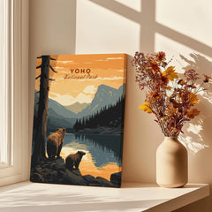 Yoho National Park art print with bears by a lake, displayed beside vase of autumn flowers on windowsill