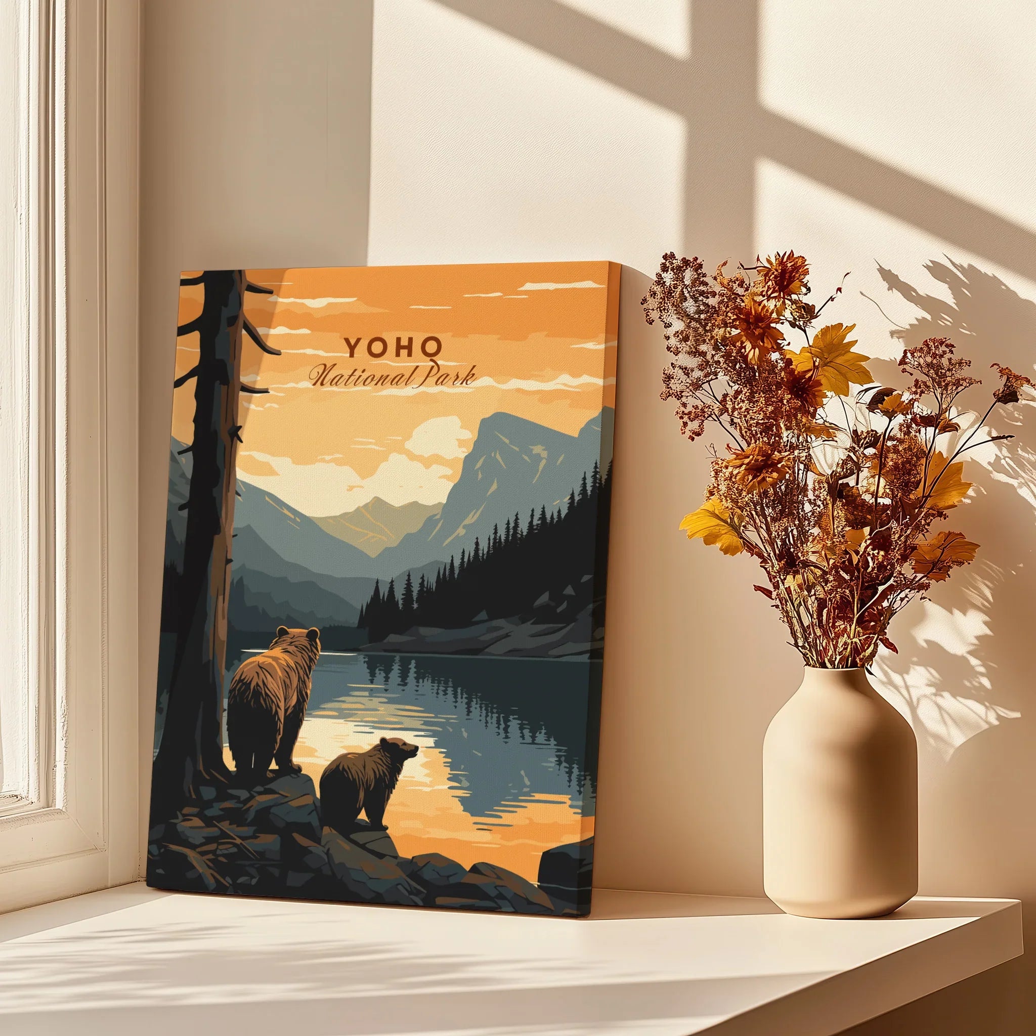 Yoho National Park art print with bears by a lake, displayed beside vase of autumn flowers on windowsill