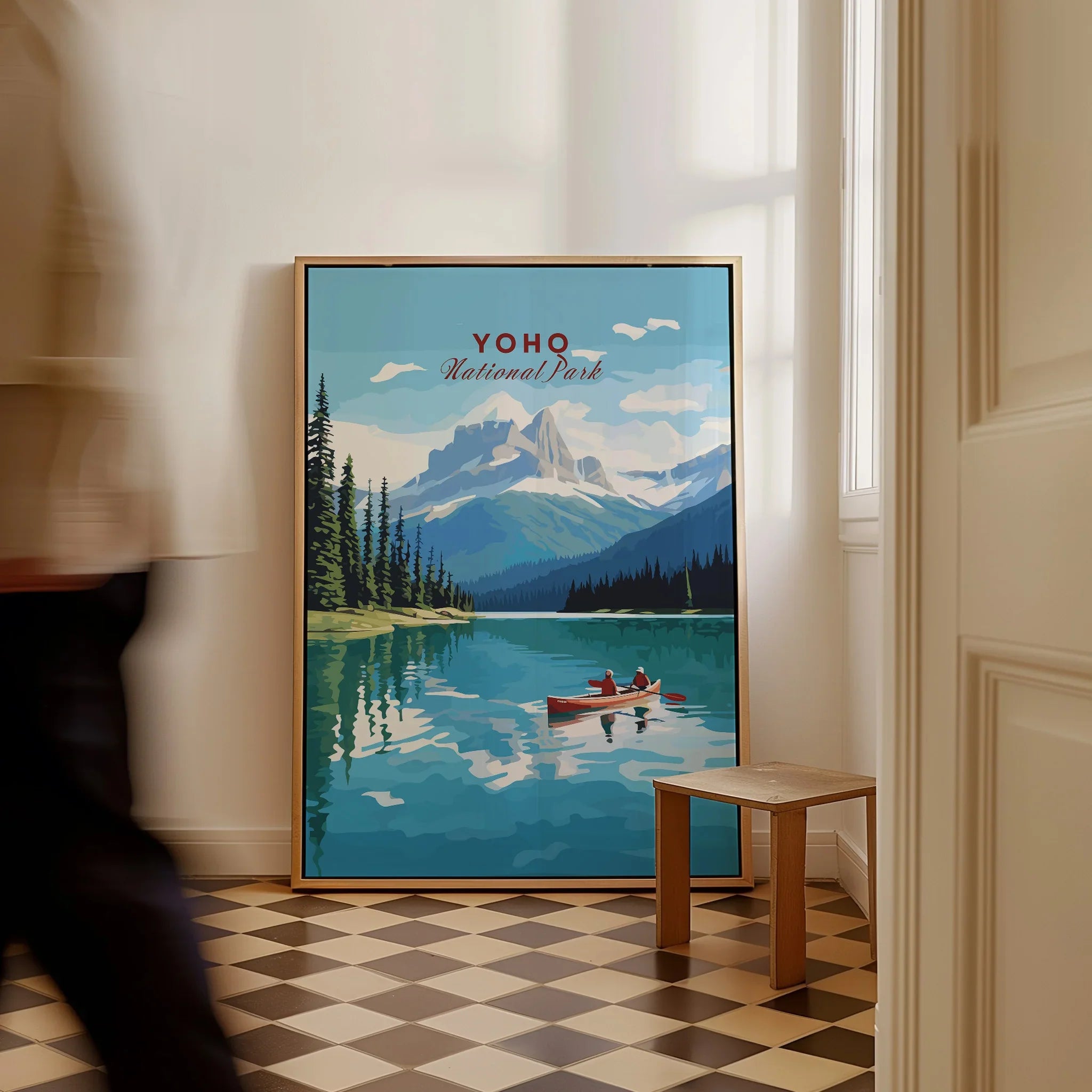 Framed Yoho National Park travel poster with mountains, lake, and canoe, leaning on floor.