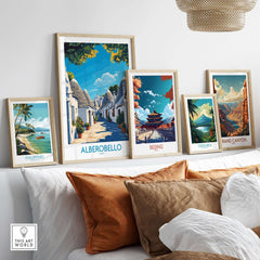 Alberobello Print Italy displayed among travel posters on a stylish couch, showcasing stunning architecture and landscapes.